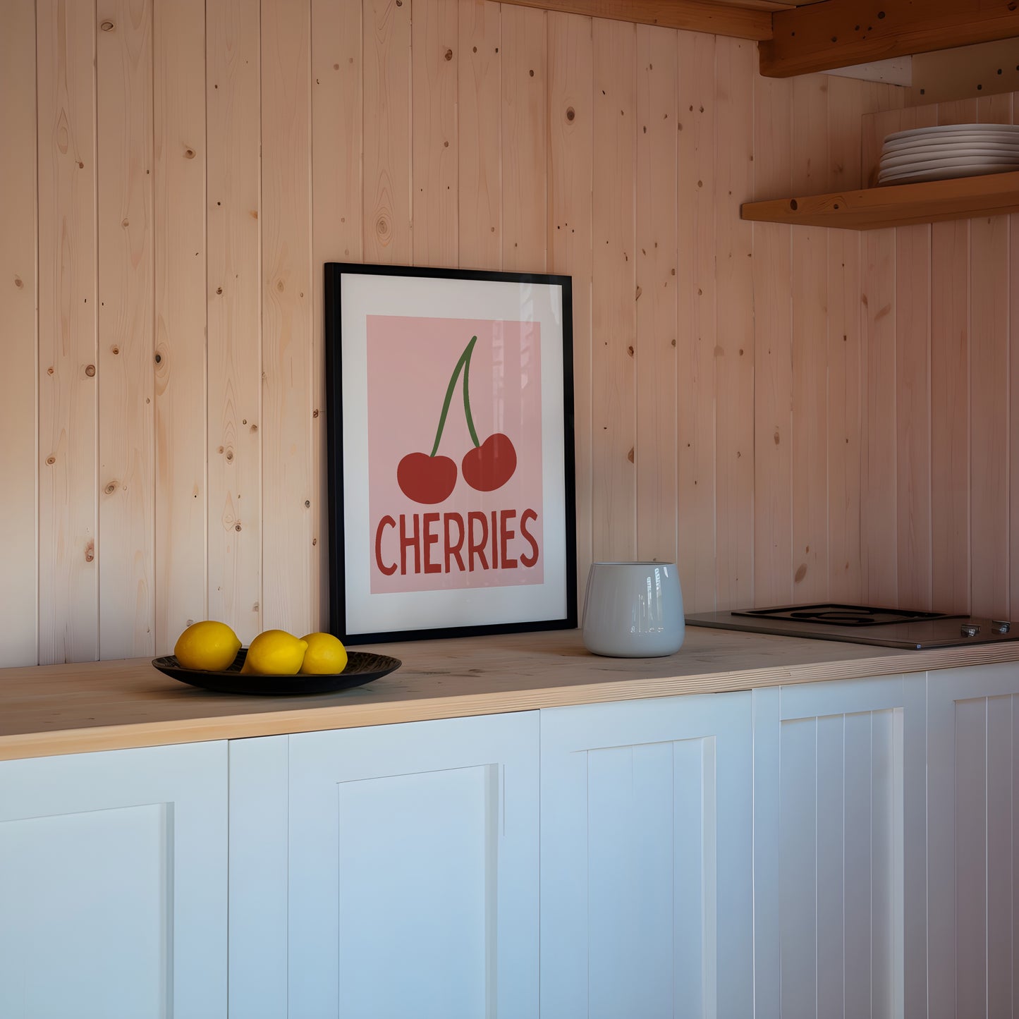 Kitchen with white cabinets, wooden wall, and a framed picture of cherries.
