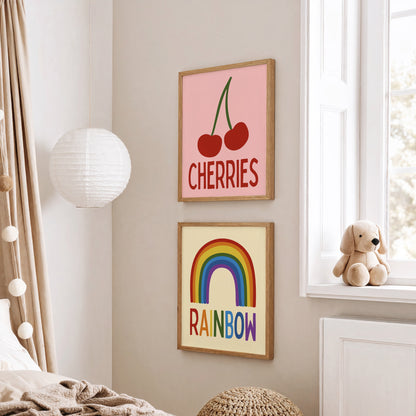 Children's room with framed artwork of cherries and rainbow, teddy bear on windowsill.