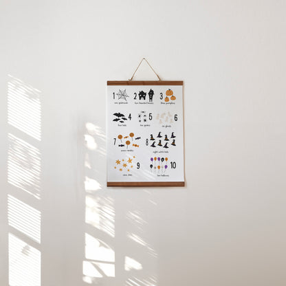 Halloween educational hanging poster with numbers and cute spooky illustrations hanging on a white wall.