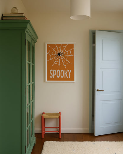 ‘Spooky’ Halloween poster featuring a spiderweb and spider on an orange background, framed on a beige wall.